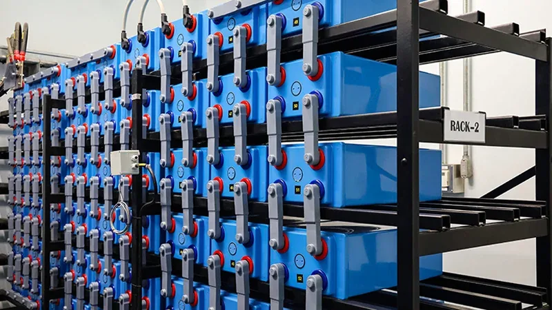 Racks of blue prismatic battery cells wired together in an energy storage system